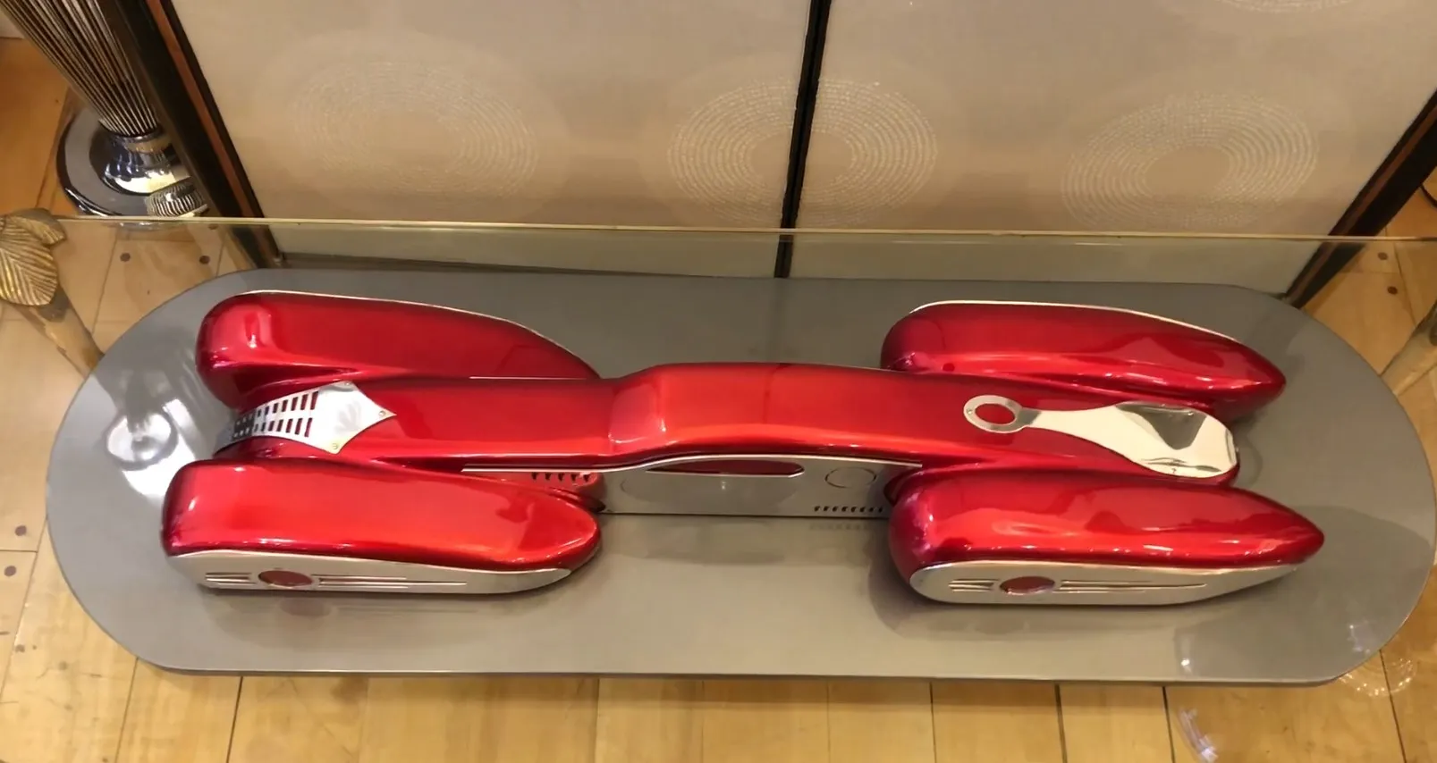 Voiture du designer Marcelo Peña dans une vitrine, couleur rouge vif, forme aérodynamique.