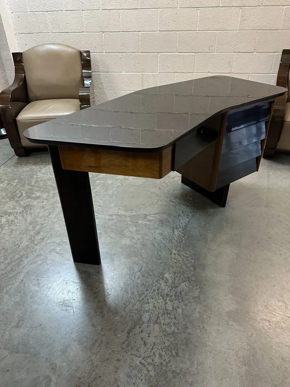 escritorio antigo com forma única e prateleira lateral, em um ambiente minimalista.