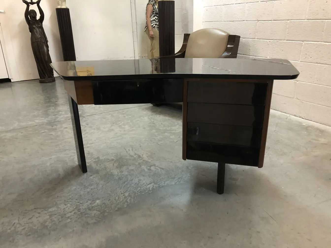 scrivania antica in legno con forma elegante in un ambiente d'antiquariato, circondata da sculture