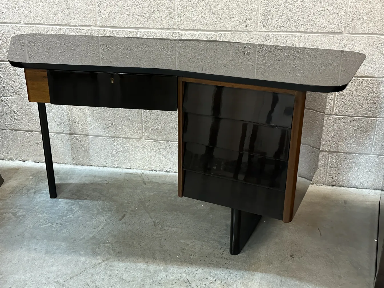 Scrivania antica con superficie nera e design elegante. Comprende un cassetto e spazio di archiviazione laterale.