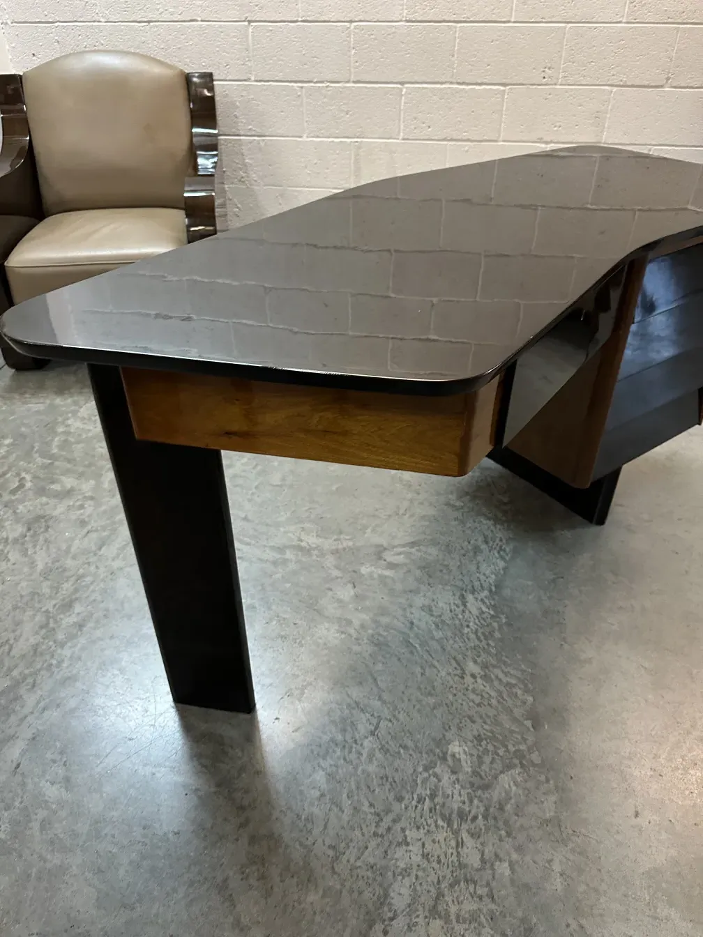 Escritorio antigo com um design curvado único e acabamentos elegantes, ao lado de uma cadeira com estofamento claro.