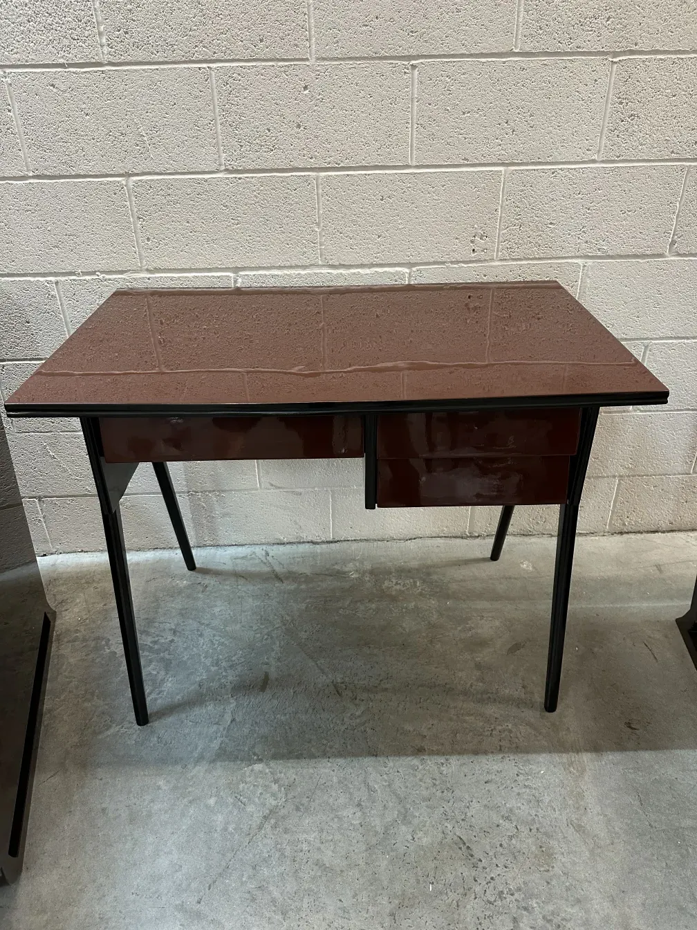 Antique desk with two drawers in a simple setting.