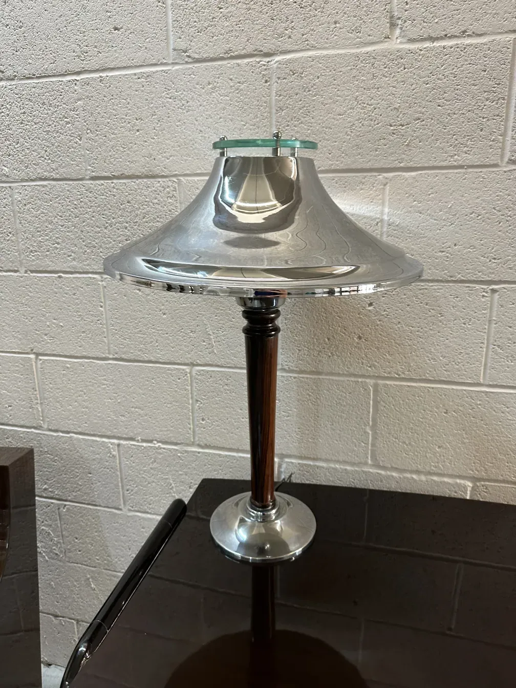Antike Tischlampe mit glänzender Metallbasis und reflektierendem Schirm, in einem eleganten Ambiente.