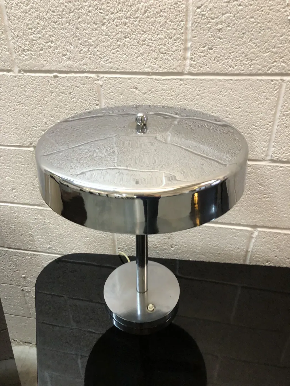 Antique table lamp with shiny base and elegant design, against a neutral background.