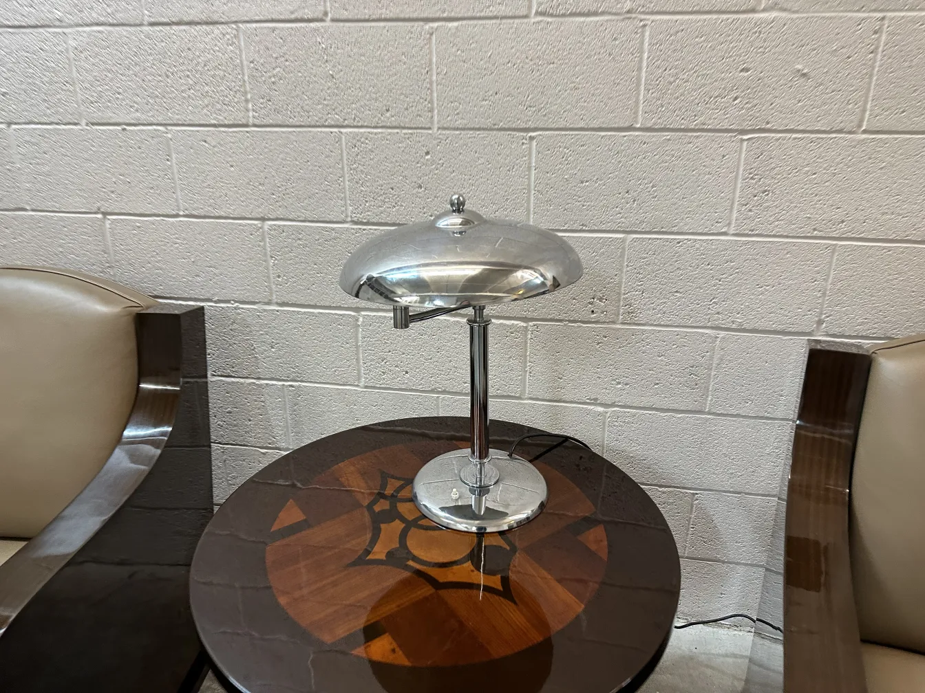 Luminária de mesa antiga em uma mesa redonda de design minimalista, com base de metal, em um ambiente elegante.