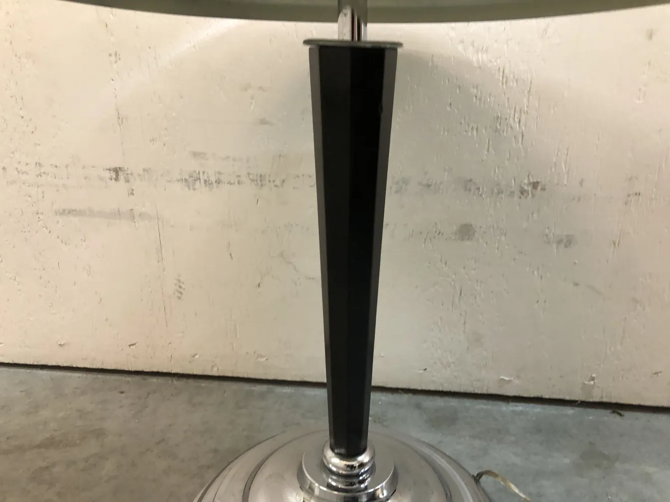 Lámpara de mesa antigua con base negra y detalles brillantes en el pie.