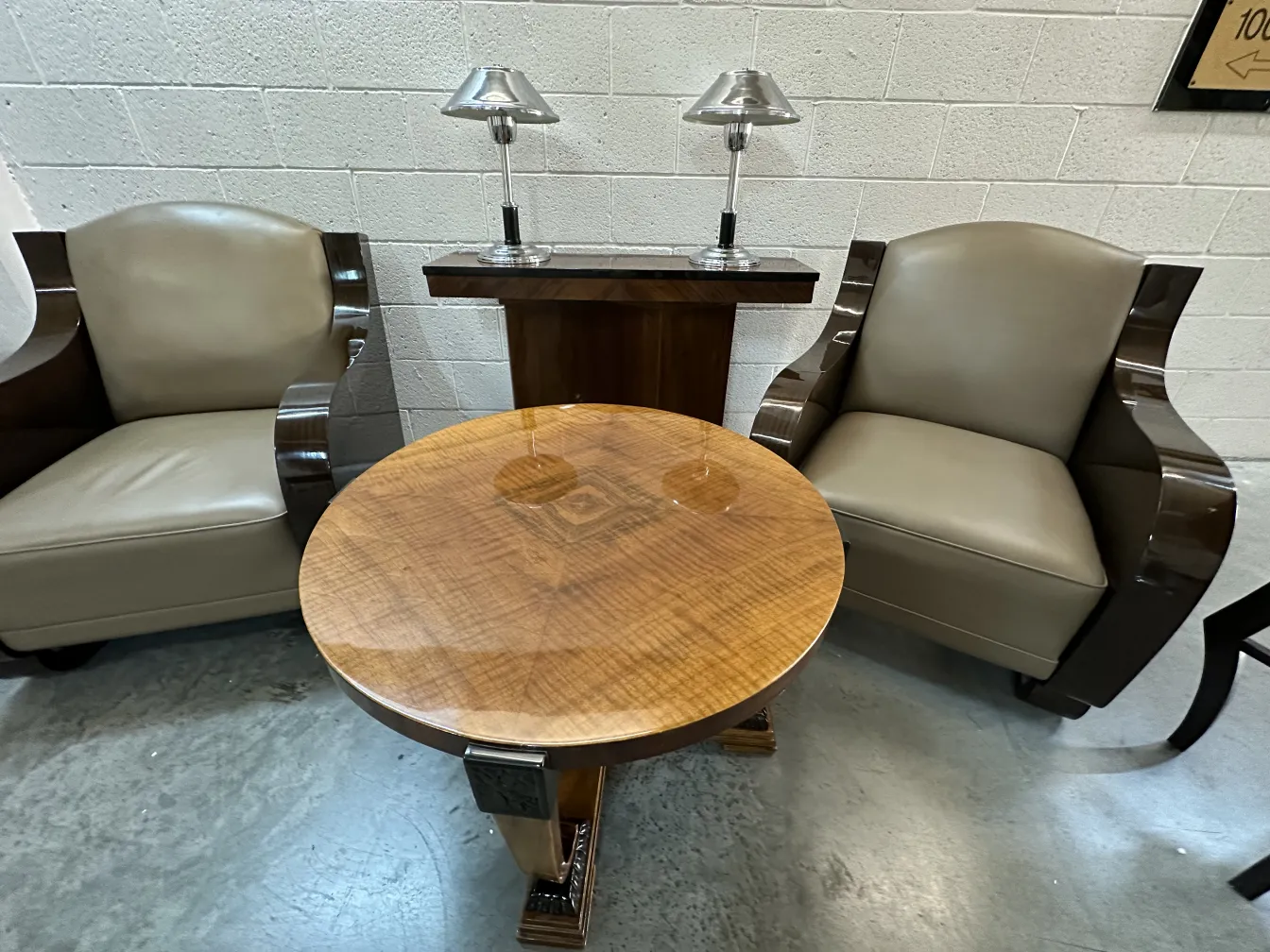 Antigua lámpara de mesa con diseño elegante, acompañada de sillones y una mesa.