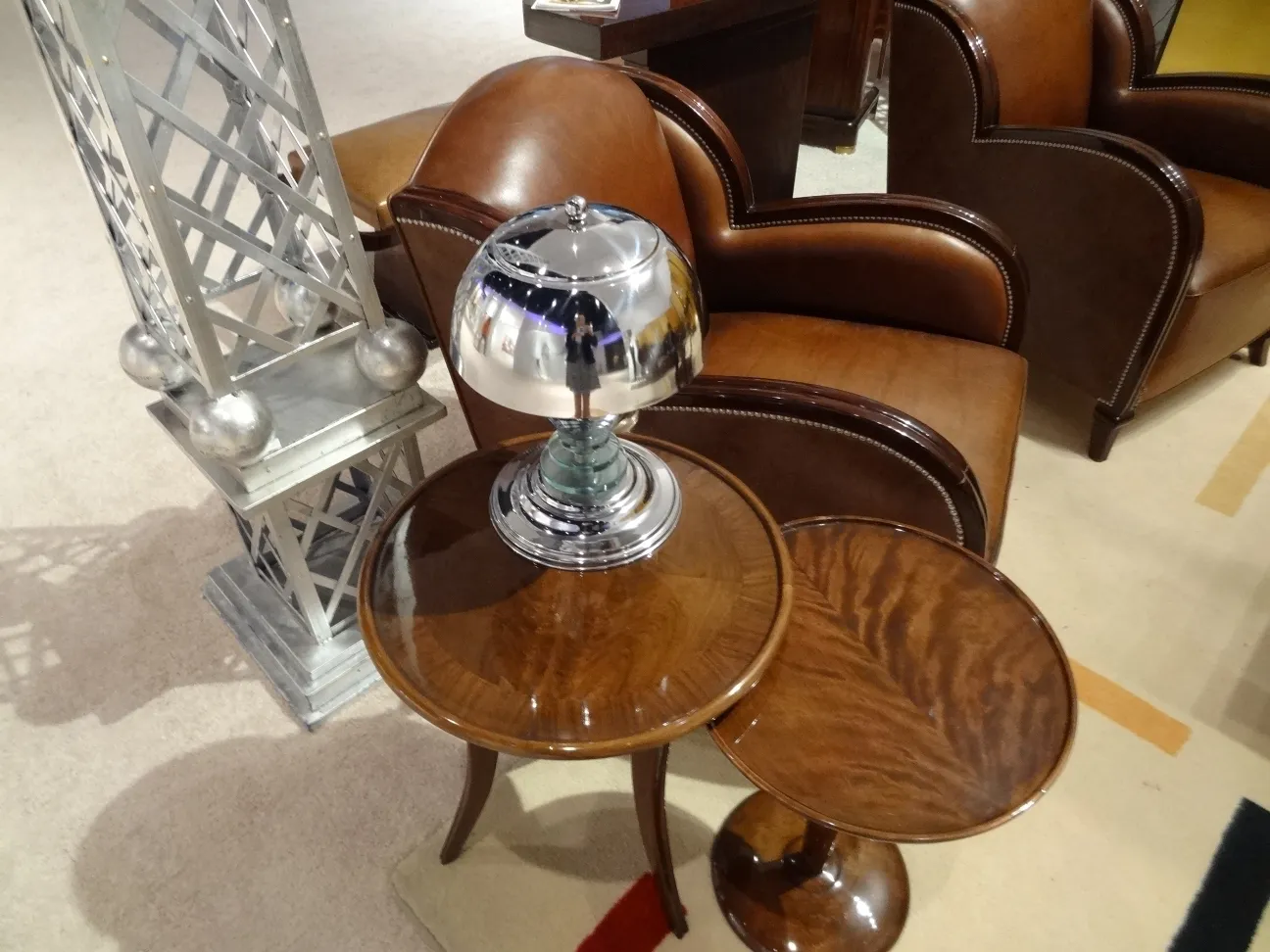 An antique table lamp with a shiny finish, next to a comfortable piece of furniture.