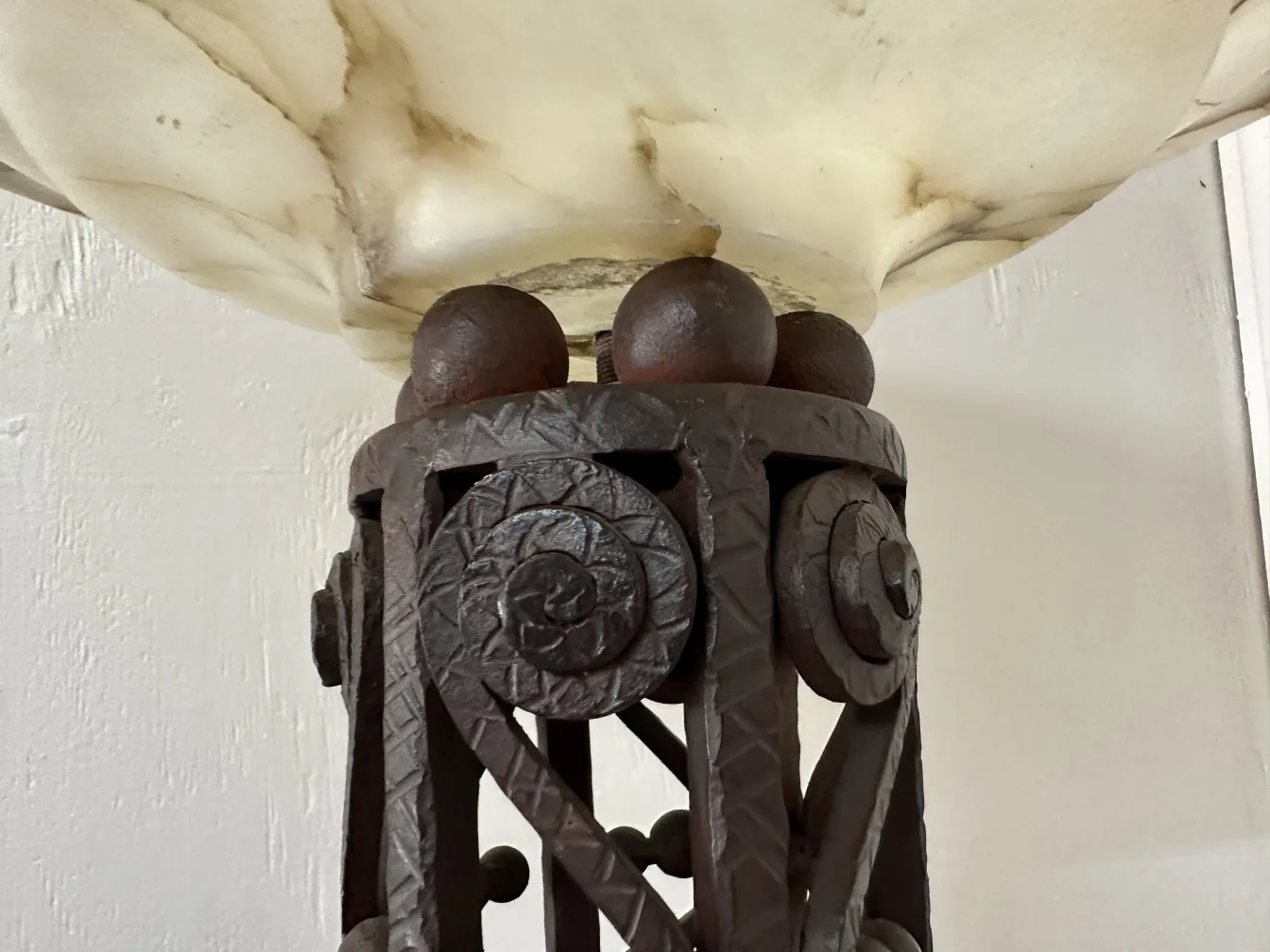 Close-up de 2 lâmpadas de piso antigas com base decorativa, em um ambiente aconchegante.