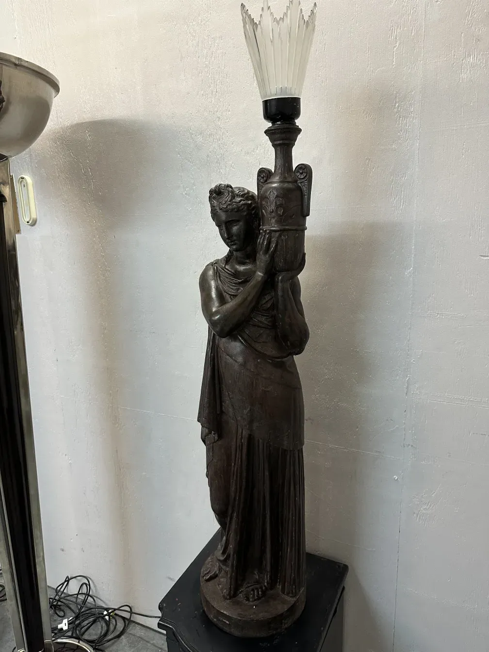 Lâmpadas de piso antigas val d´osne em um ambiente elegante, com figura segurando um suporte decorativo.