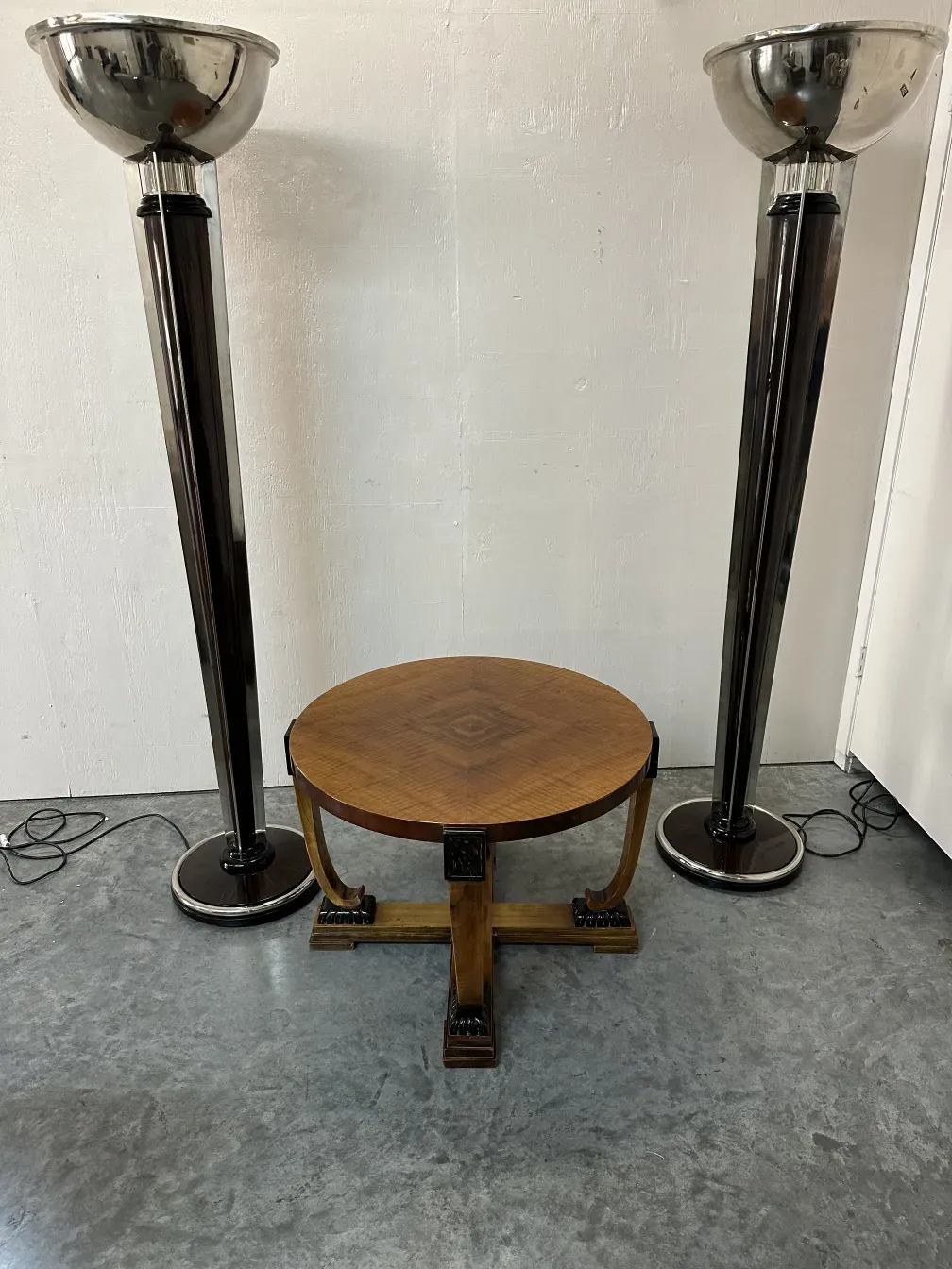 Zwei antike Armlehnstühle in einer modernen Umgebung. Lampen und ein runder Tisch sind sichtbar.