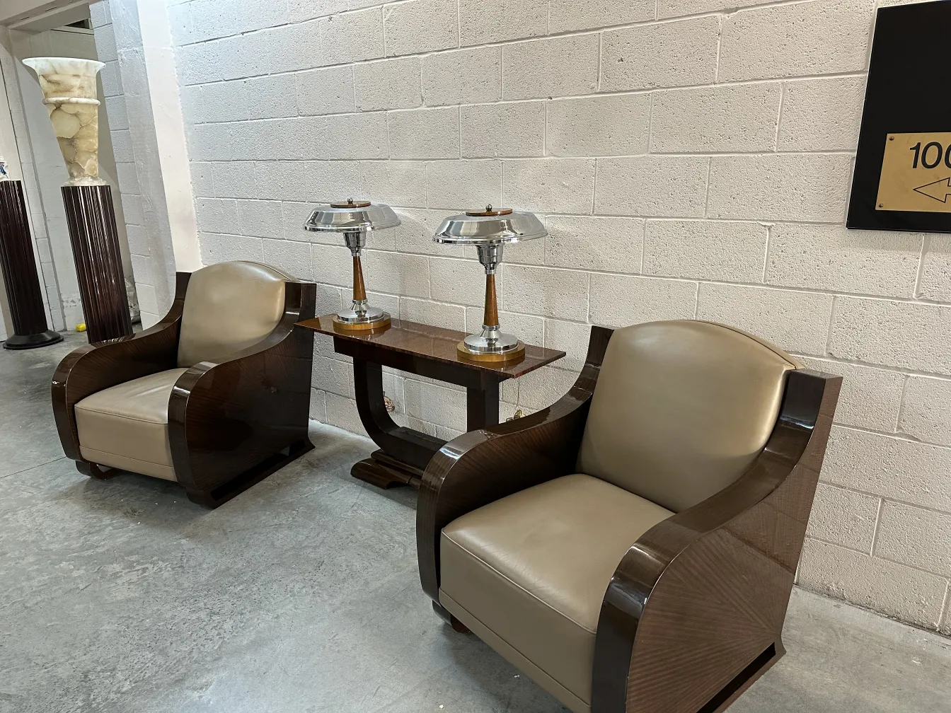 Deux fauteuils anciens avec rembourrage clair et forme courbée, à côté de lampes et d'une table.