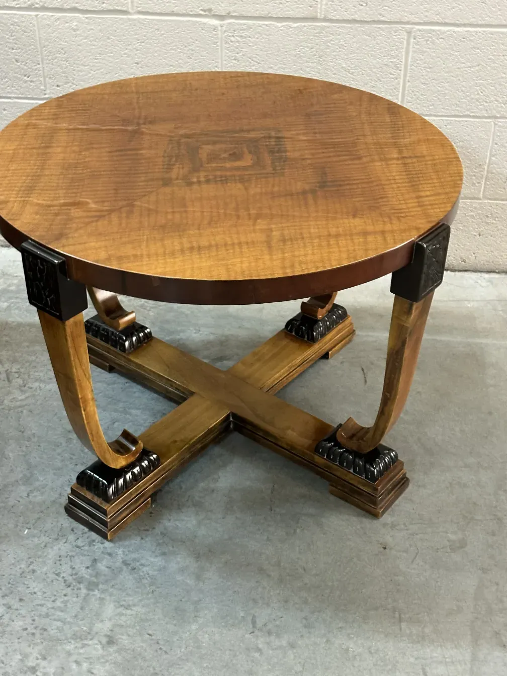 Antique round coffee table with X-shaped base, simple background.