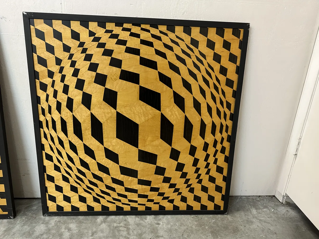 Antico intarsio decorativo con motivo geometrico nei toni oro e nero.