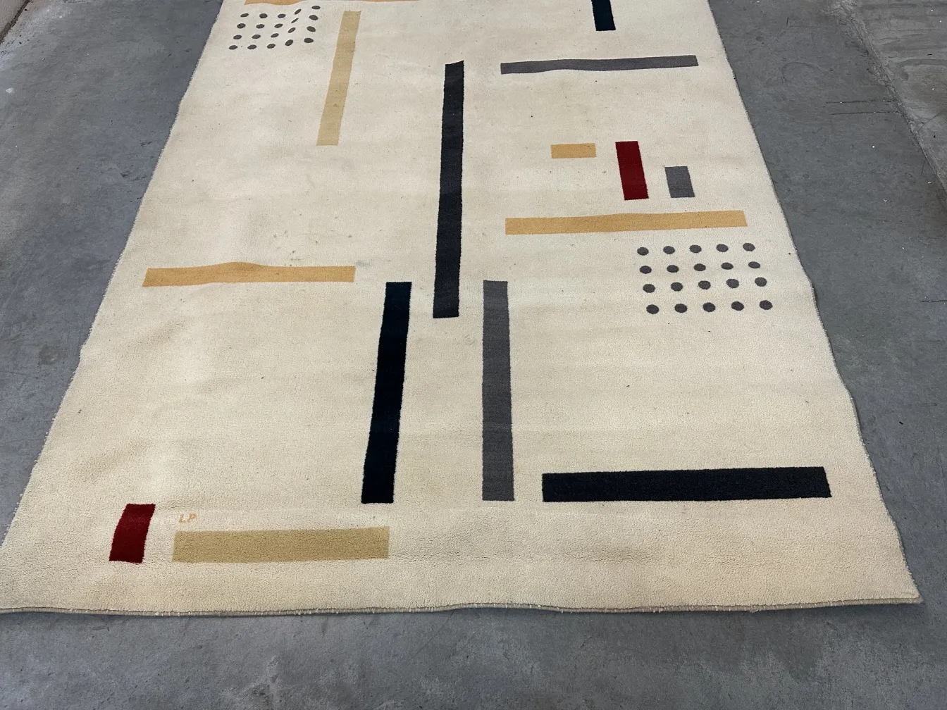 Tapis ancien avec motifs géométriques colorés et fond clair.