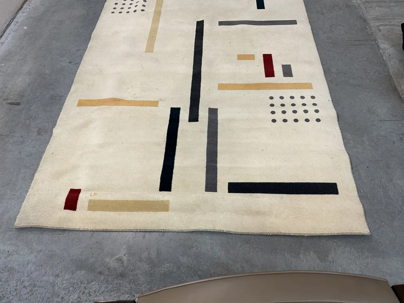 Tappeto antico con design geometrici in beige e nero, stile astratto.