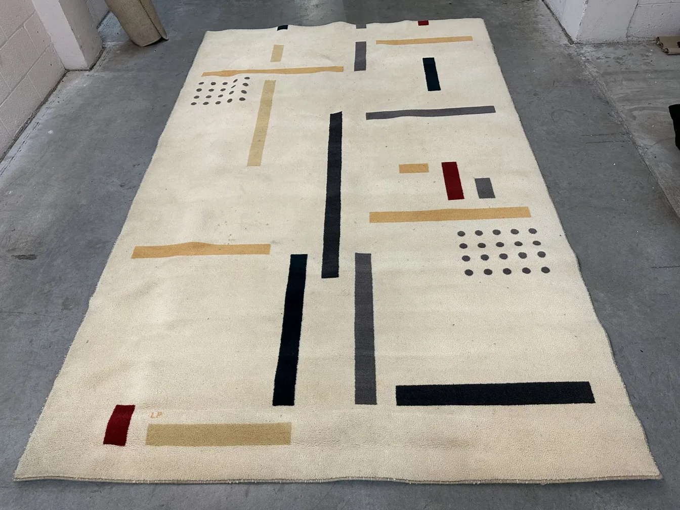 alfombra antigua de color claro con diseños geométricos en tonos oscuros y claros, en un ambiente moderno