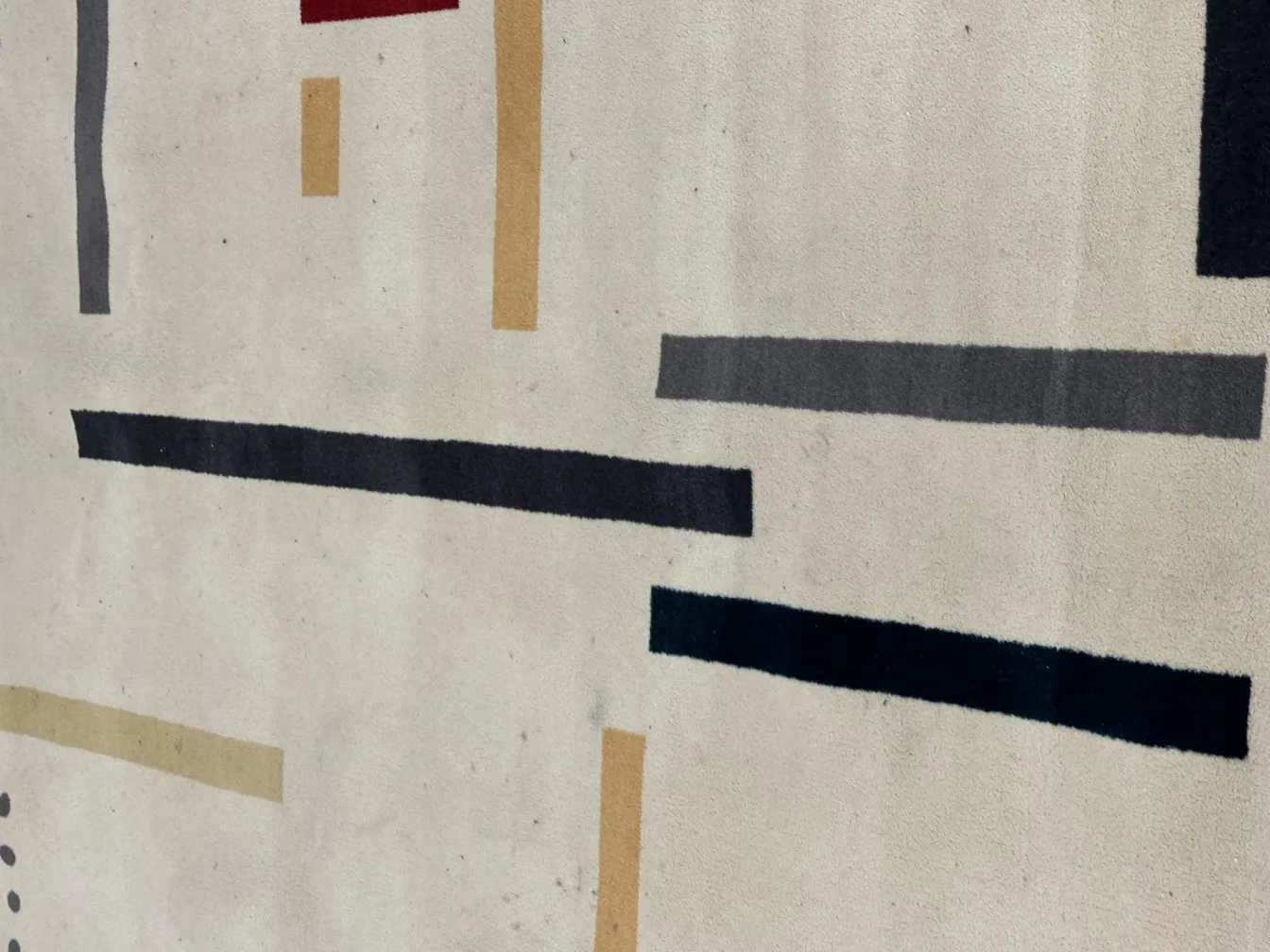 Tappeto antico con motivi geometrici in tonalità chiare e scure.