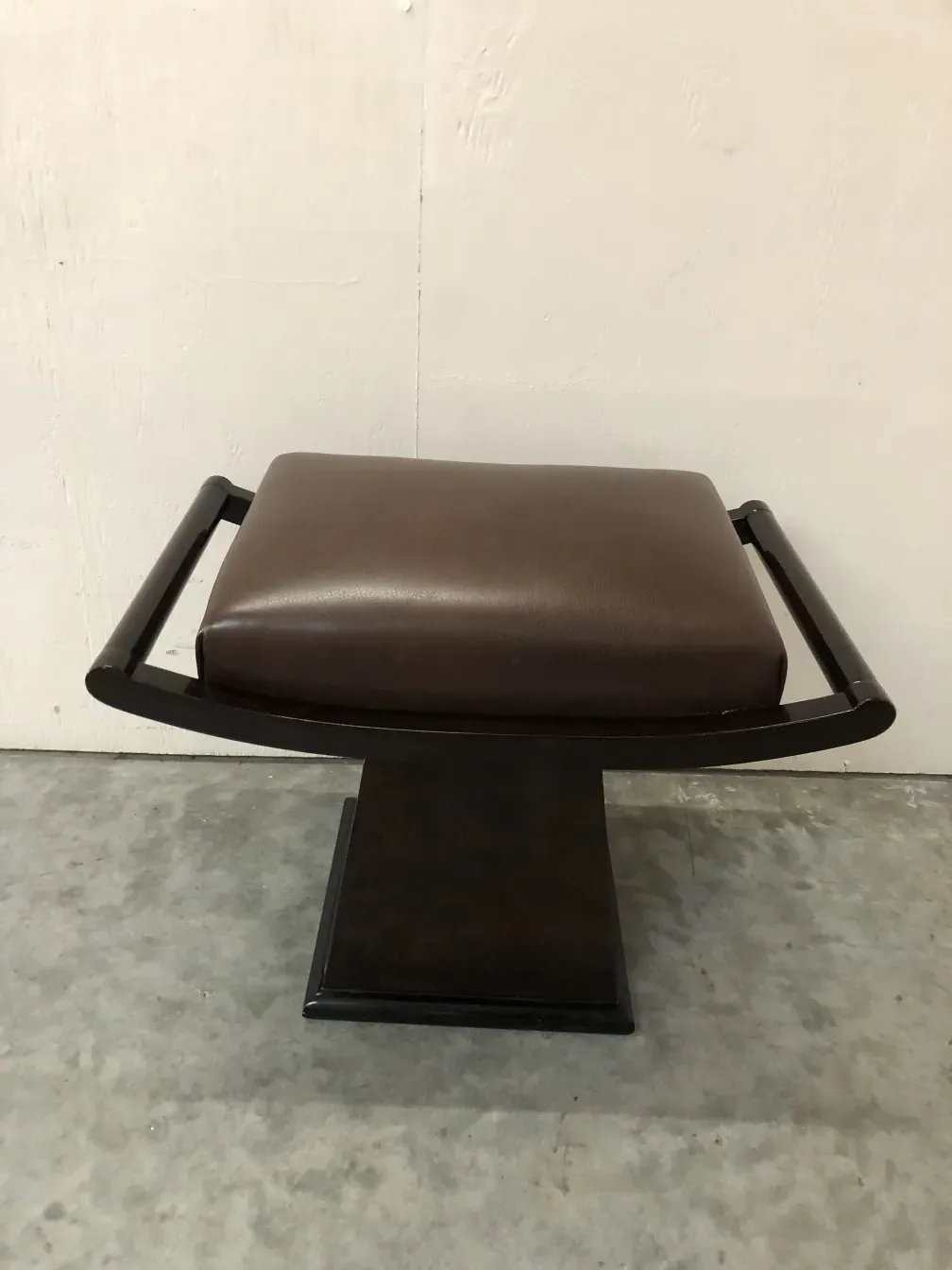 antique stool with elegant shape and brown padding in a neutral setting