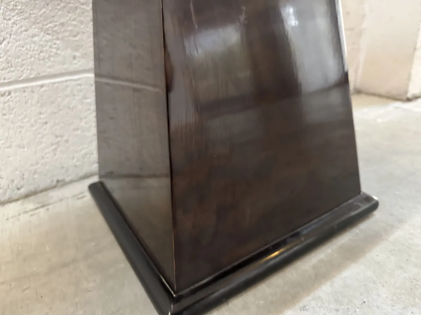 Vue latérale d'un tabouret ancien avec une base noire dans un cadre rustique.