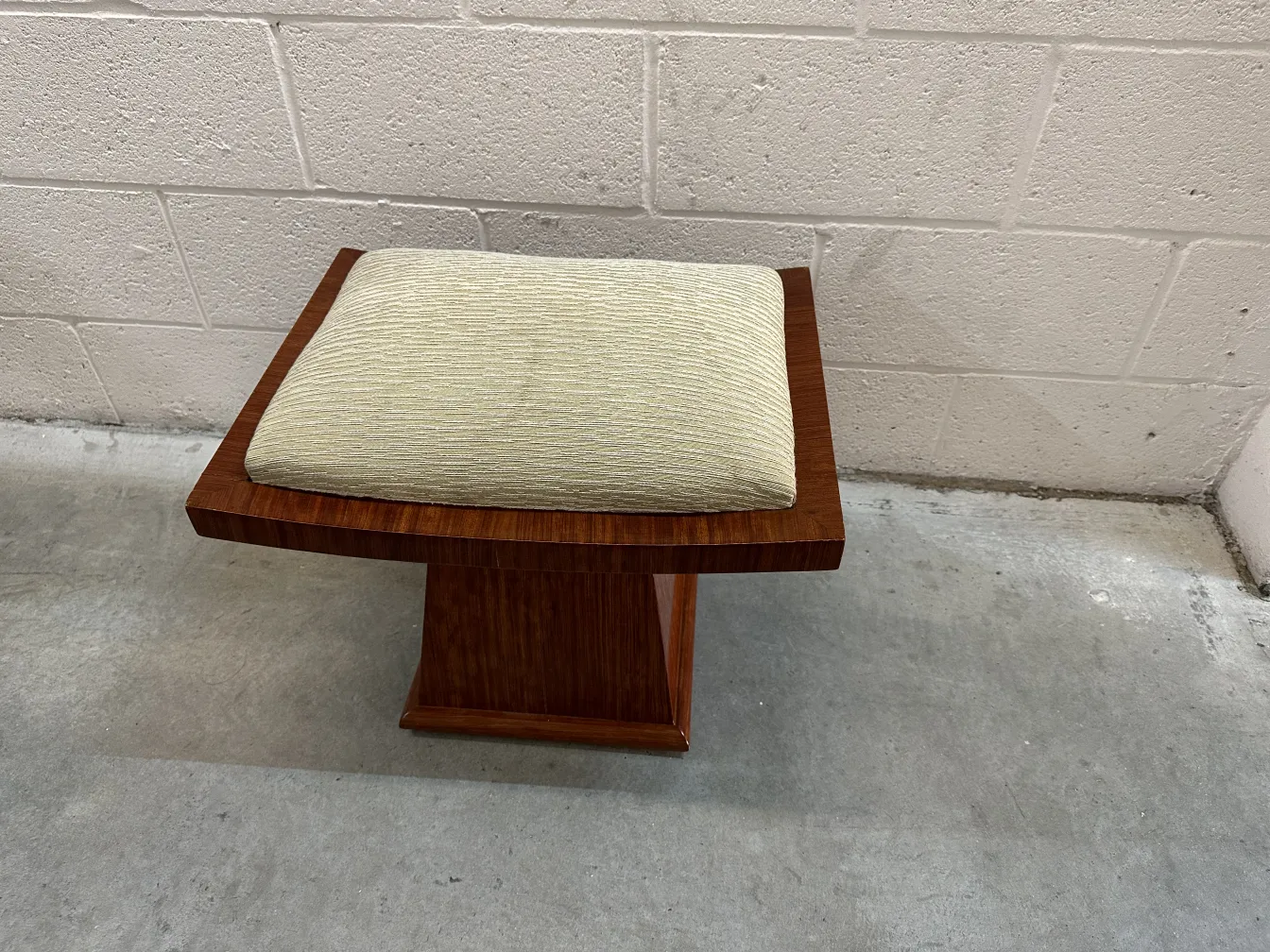 Tabouret ancien avec coussin clair, fond neutre
