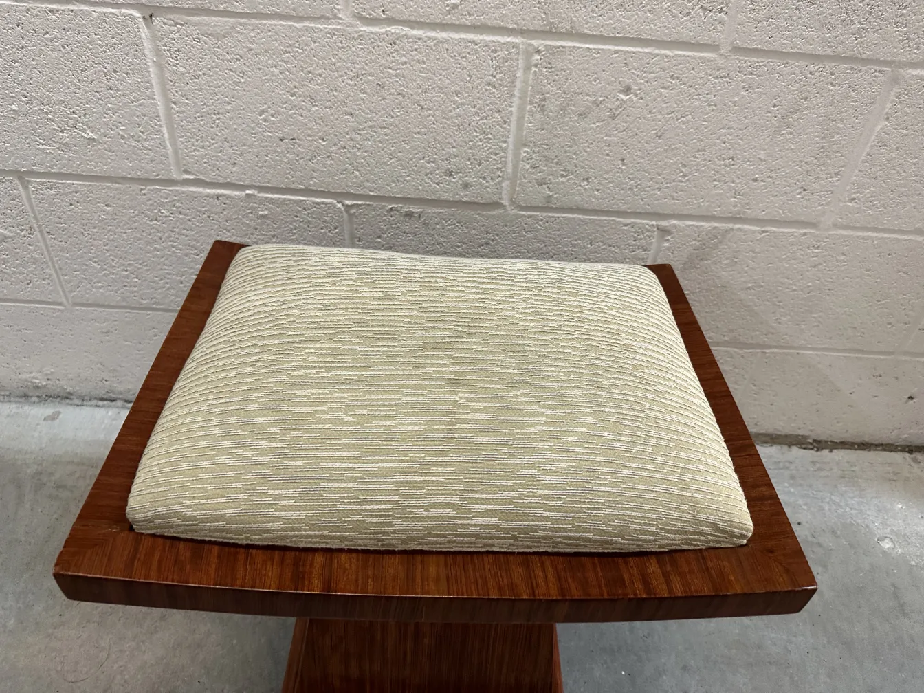 Antiker Hocker mit Kissen in einfacher Umgebung