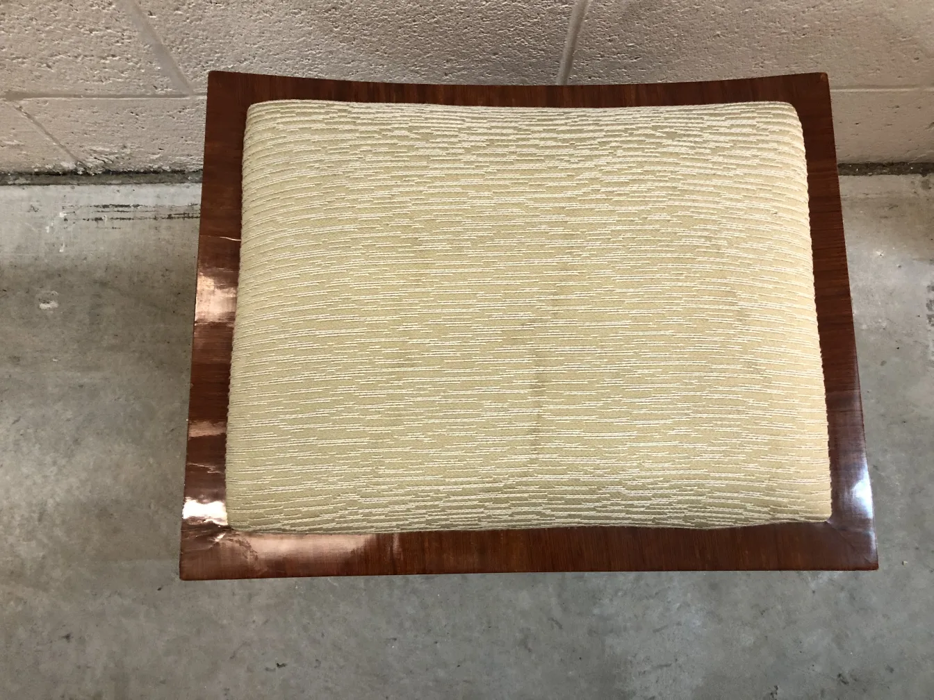 Antiker dekorativer Hocker mit hellem Kissen, neutrale Umgebung.