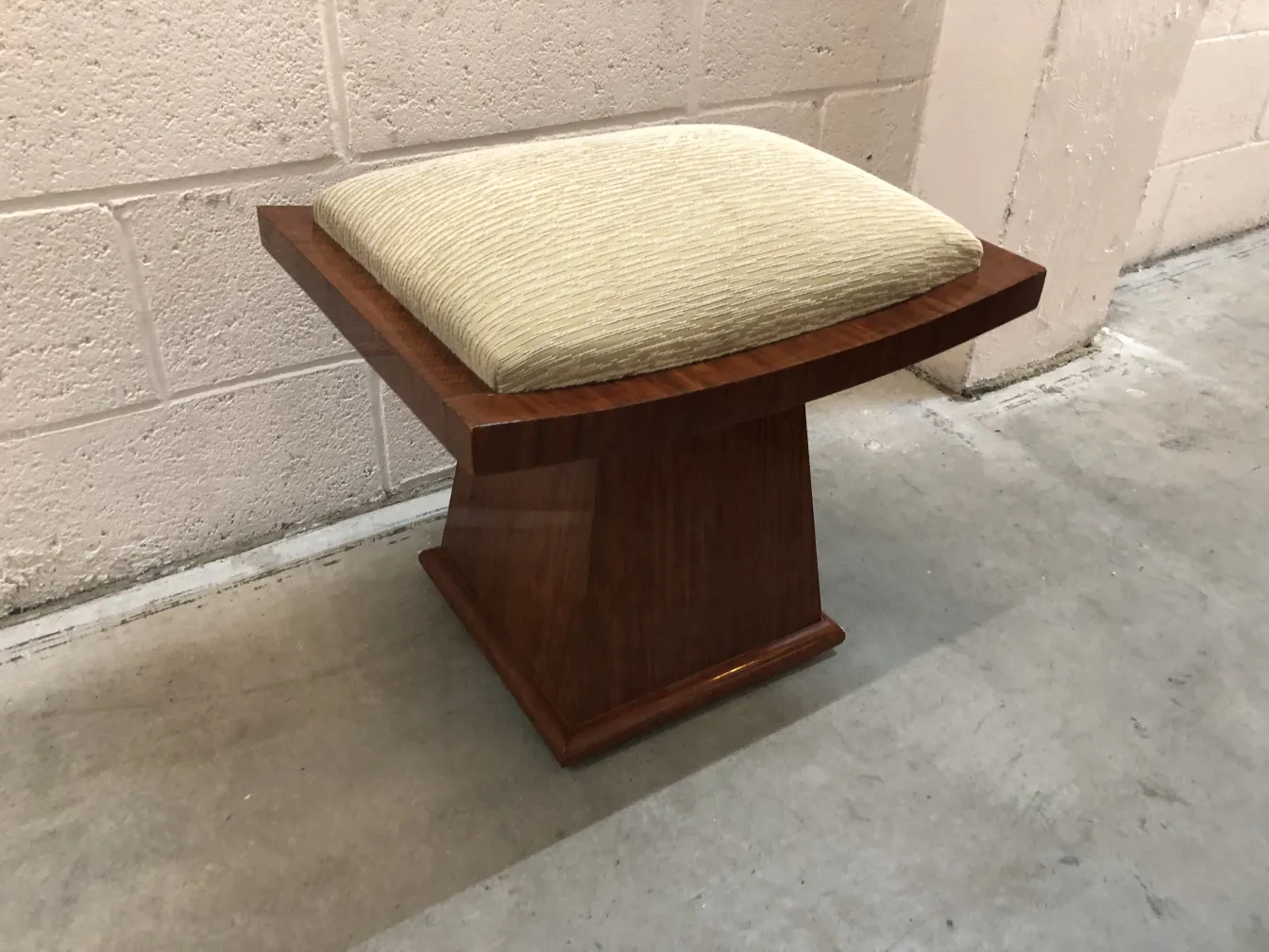 Antiker Hocker mit weichem Sitz in neutraler Umgebung.