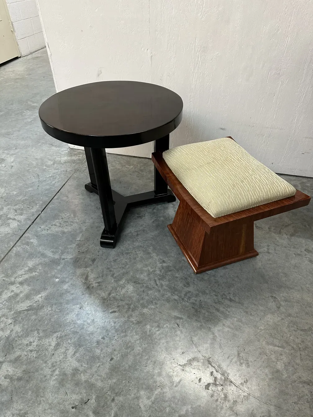 Banqueta antiga com assento macio, ao lado de uma mesa redonda