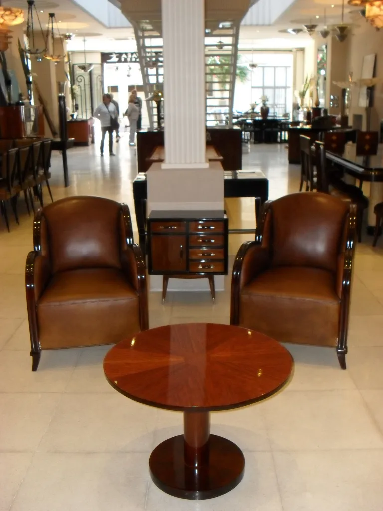 Antiker kleiner Tisch mit glänzender Oberfläche, runde Form, in einem eleganten Ambiente mit Ledersesseln.