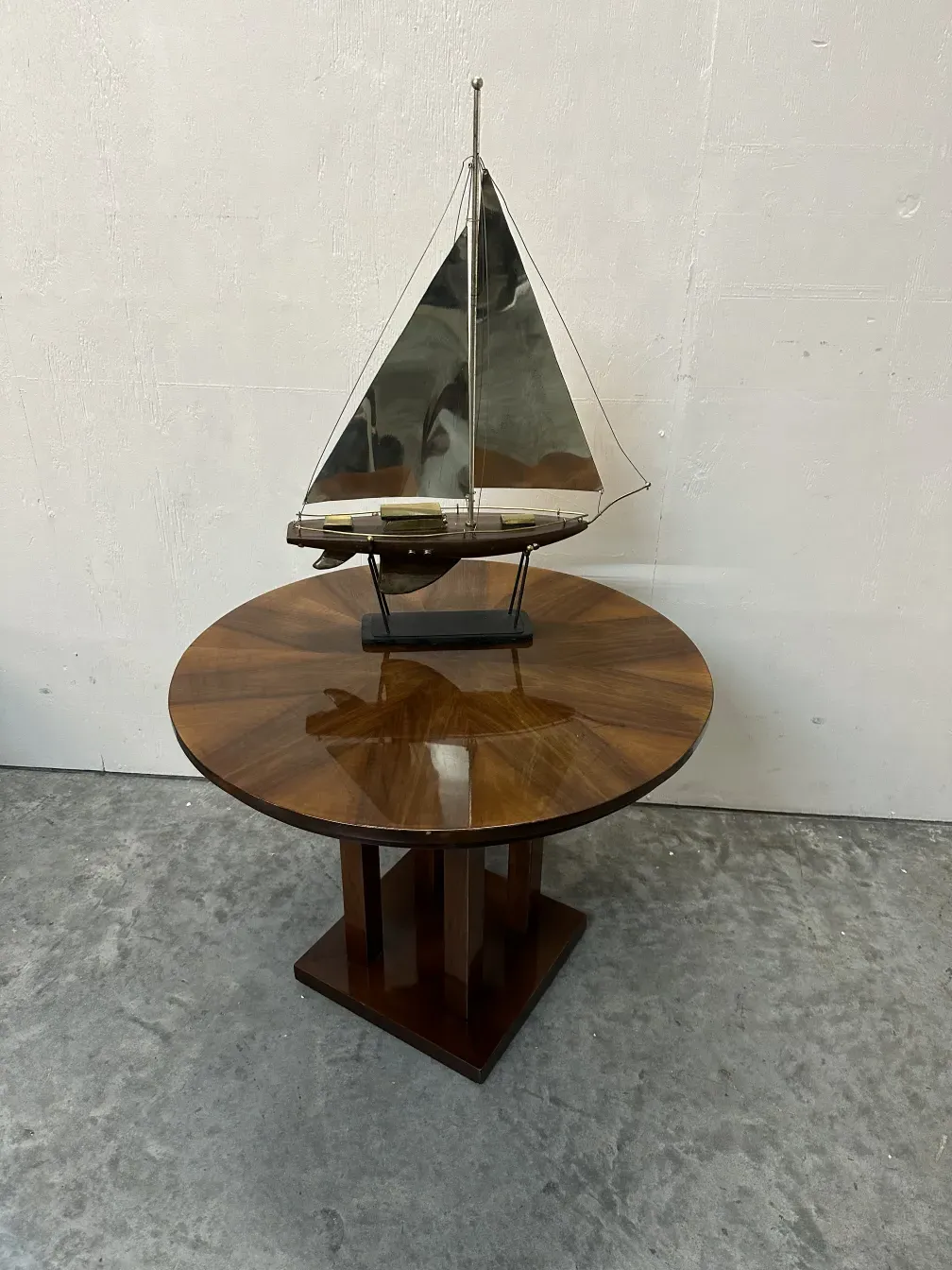 petite table antique avec un bateau à voile sur le dessus, sur une surface claire, fond gris