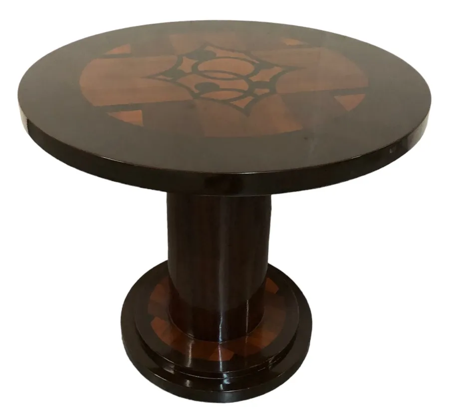 Petite table ancienne ronde avec détails sombres et design central.