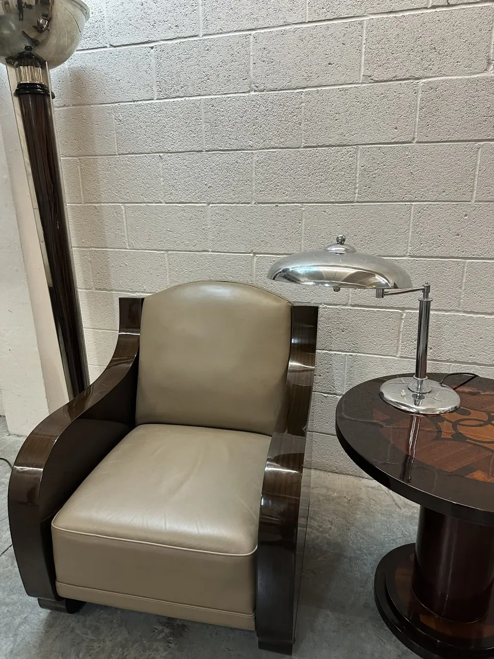 Petite table antique décorative à côté d'un fauteuil clair dans une salle moderne.