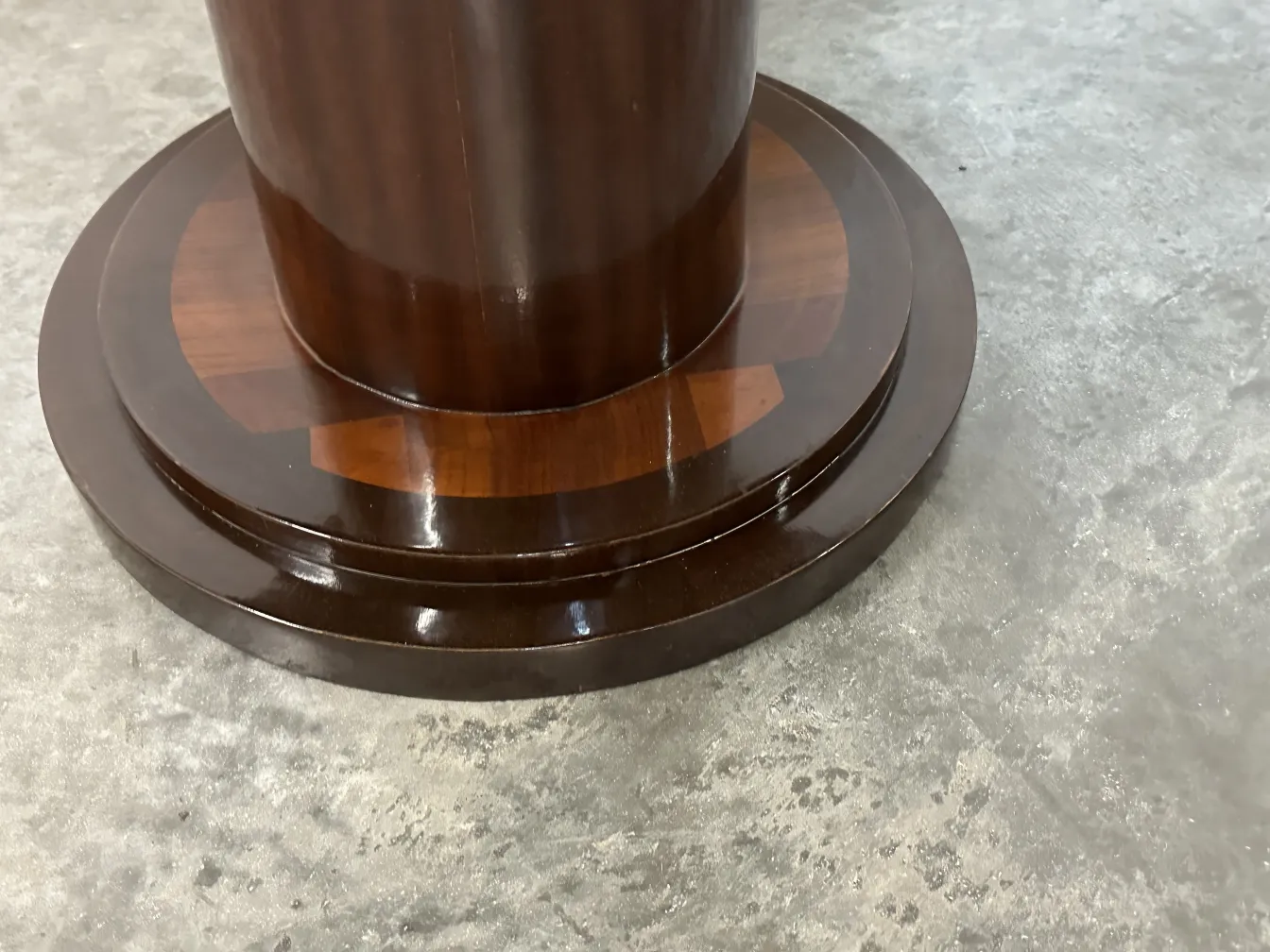 detalhe da base de uma mesa pequena antiga redonda com acabamento brilhante.