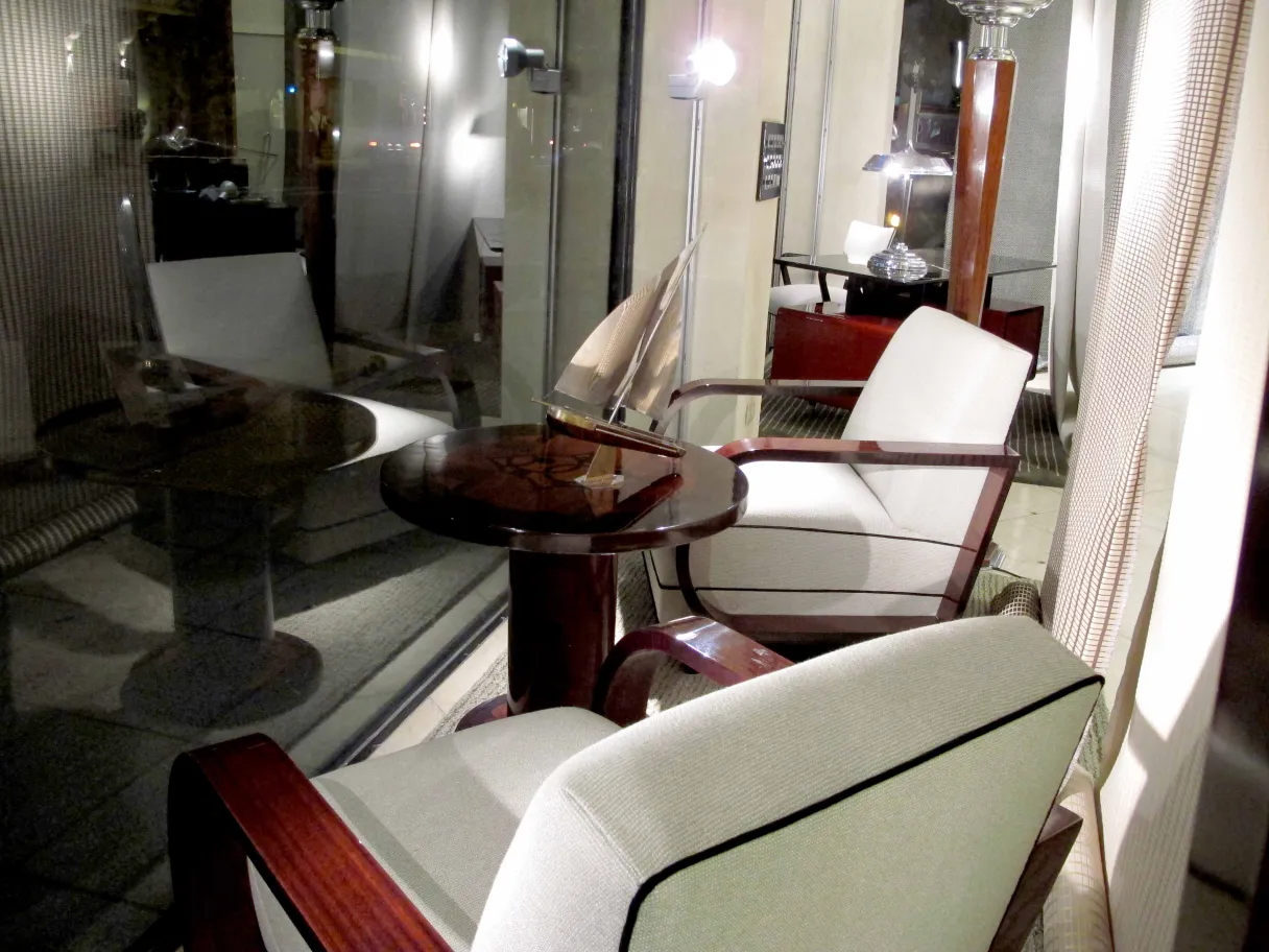 Mesita antigua pequeña junto a sillones en un ambiente acogedor.