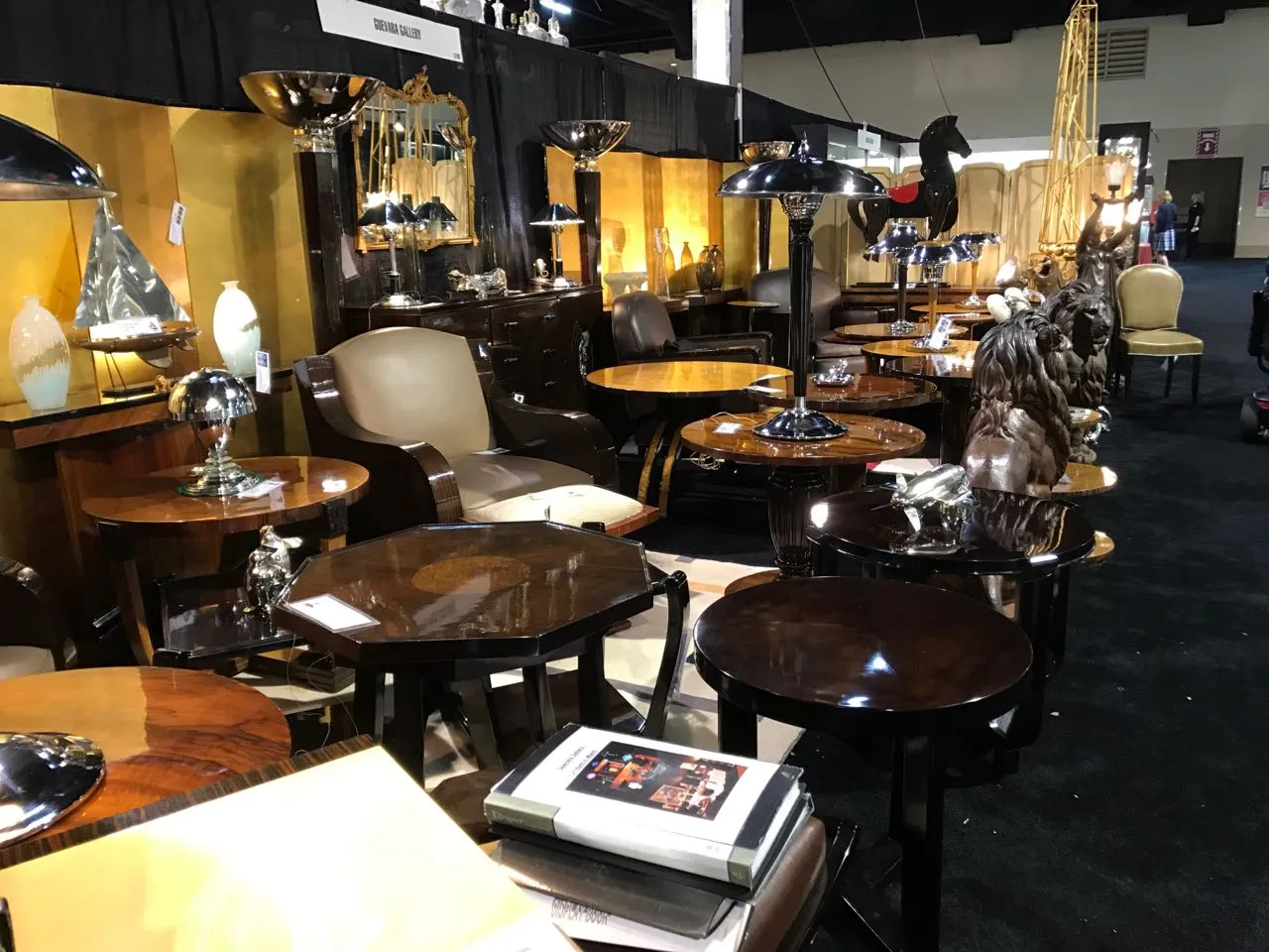 Mesita antigua de madera con detalles decorativos, rodeada de otros muebles