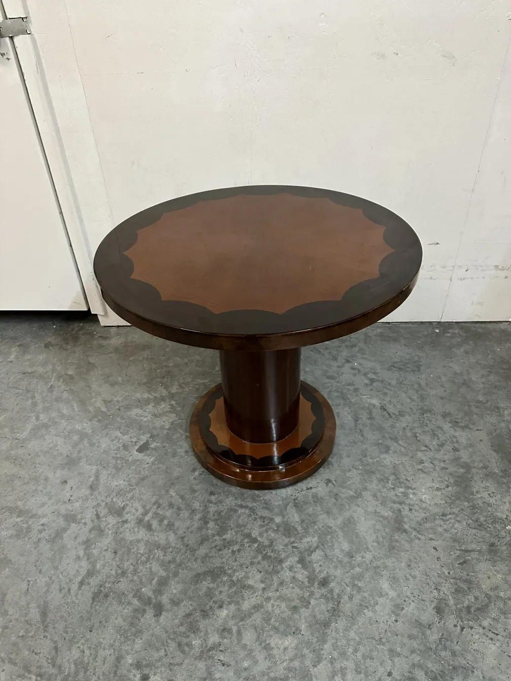 Ancienne petite table ronde avec détails décoratifs, ambiance vintage.