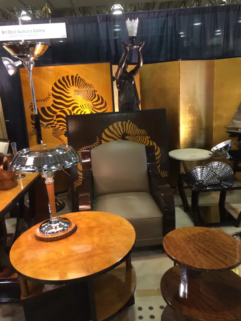 Mesita antigua disponible en un salón con muebles elegantes y una escultura decorativa.