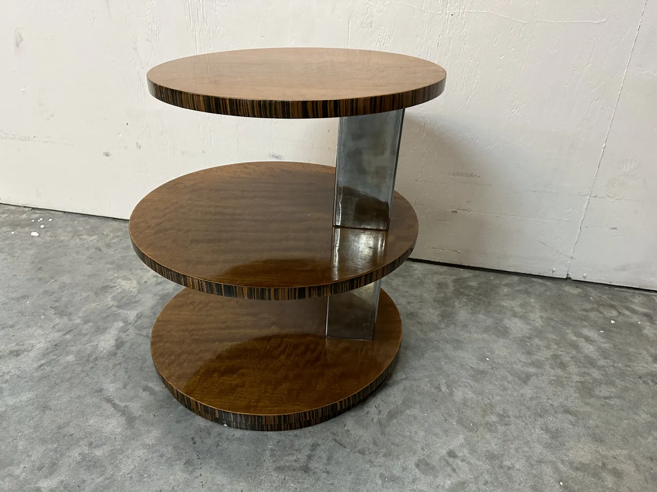 Petite table ancienne à trois niveaux avec base solide dans un cadre minimaliste.