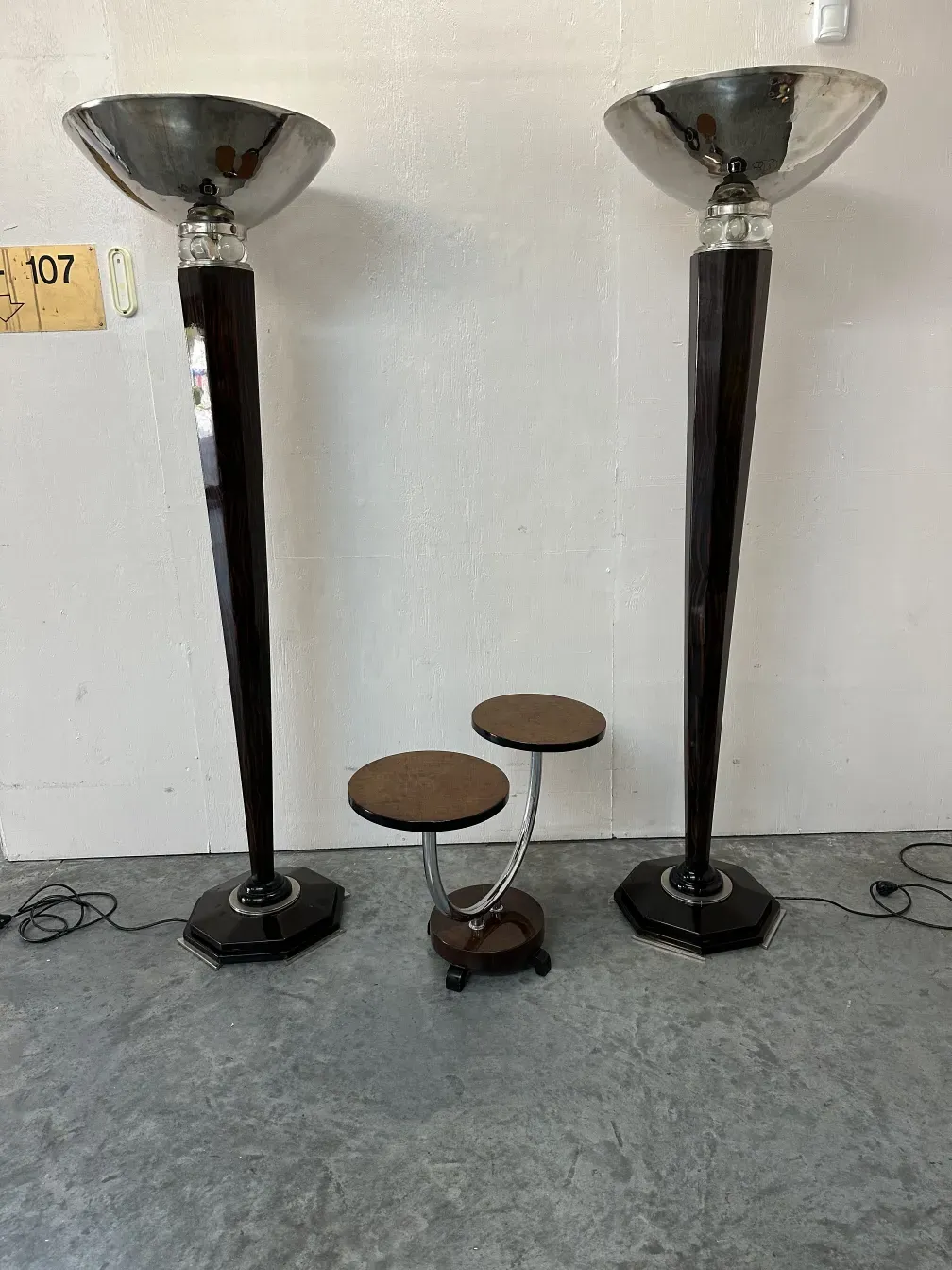Antique small table with two tiers in a minimalist setting, flanked by lamps.