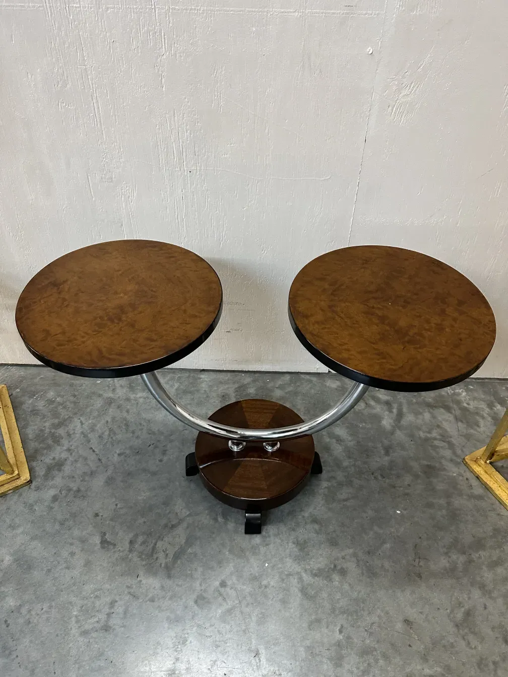 Mesinha antiga com duas superfícies redondas e base metálica.