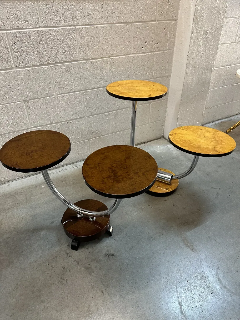 Petite table ancienne avec base ronde et pattes mobiles multiples, dans un environnement neutre