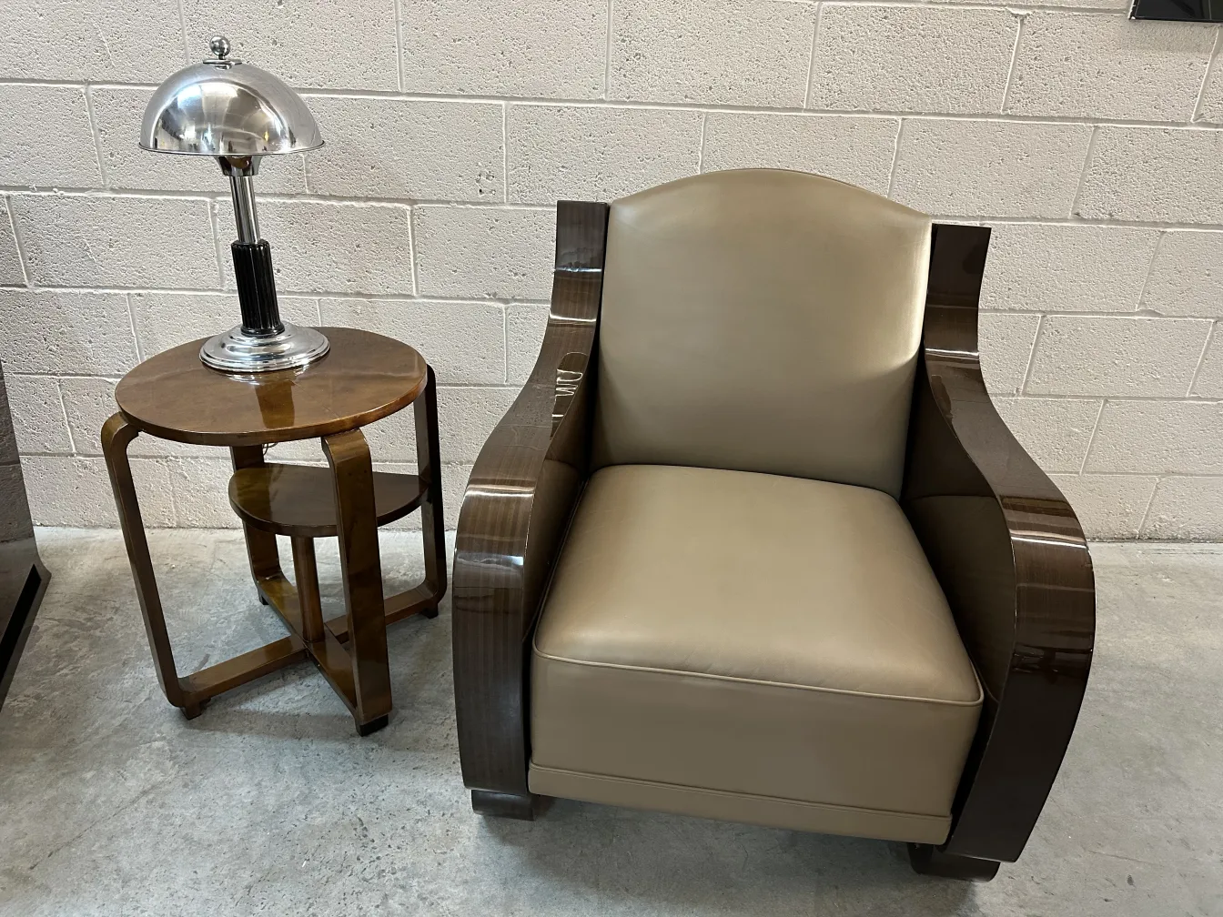 Petite table ancienne brillante à côté d'un fauteuil et d'une lampe.