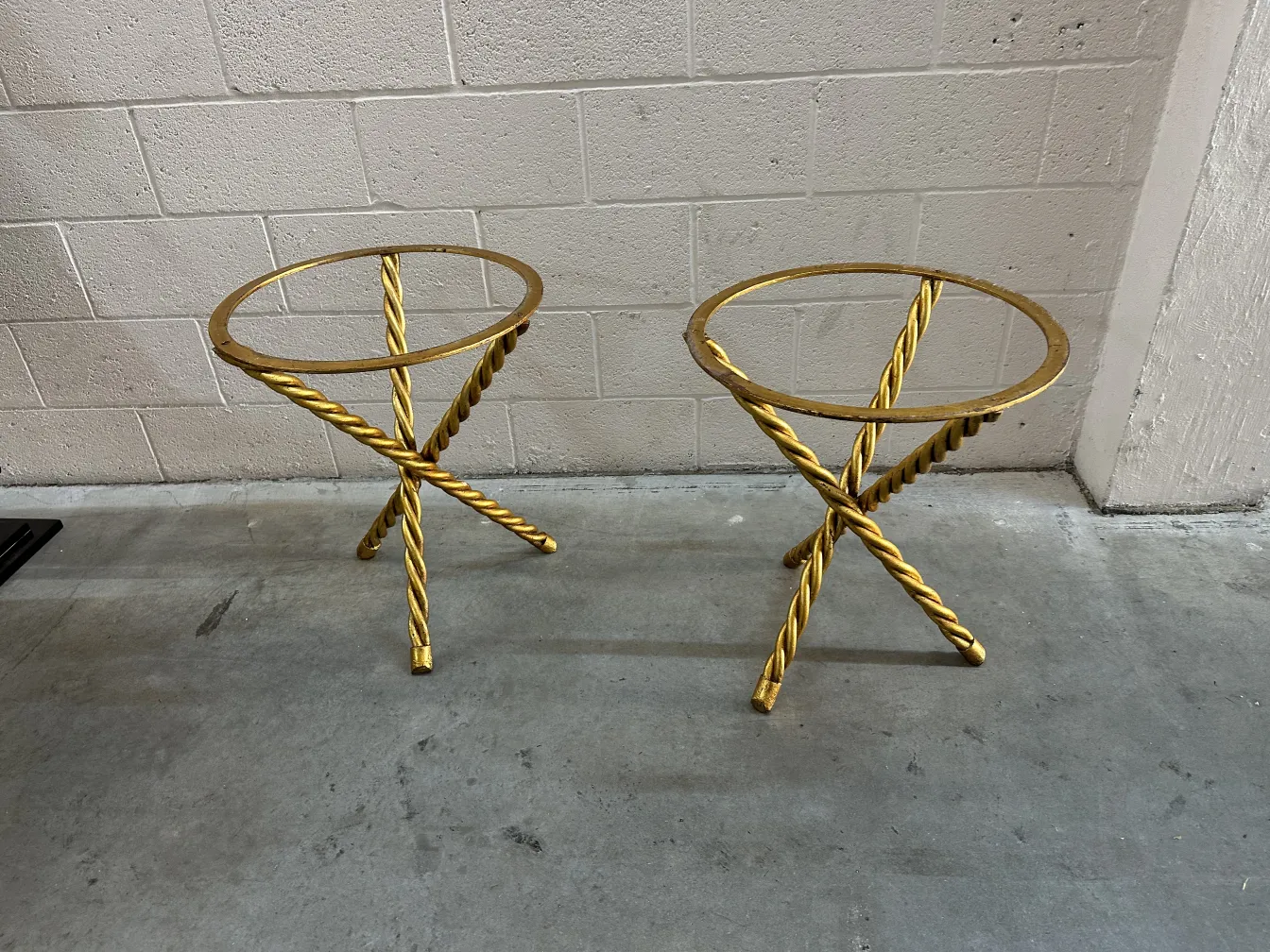 Dos mesitas doradas de antigüedades con diseño entrelazado.