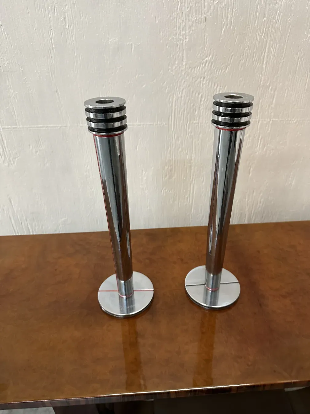 2 antike kerzenhalter aus Metall auf einem Holztisch, sanft beleuchtet.