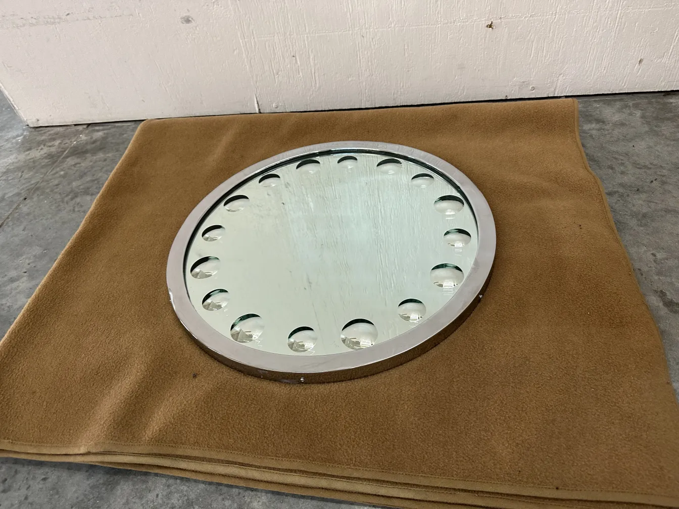 Espejo antiguo redondo sobre fondo suave con detalles decorativos.