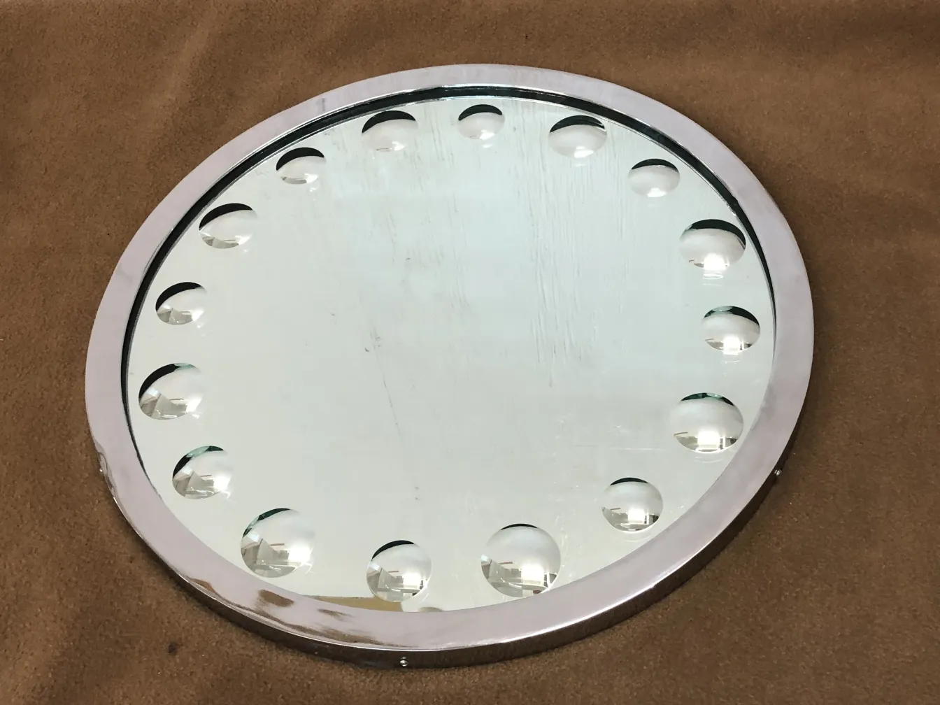 miroir ancien rond avec des détails en relief, fond marron