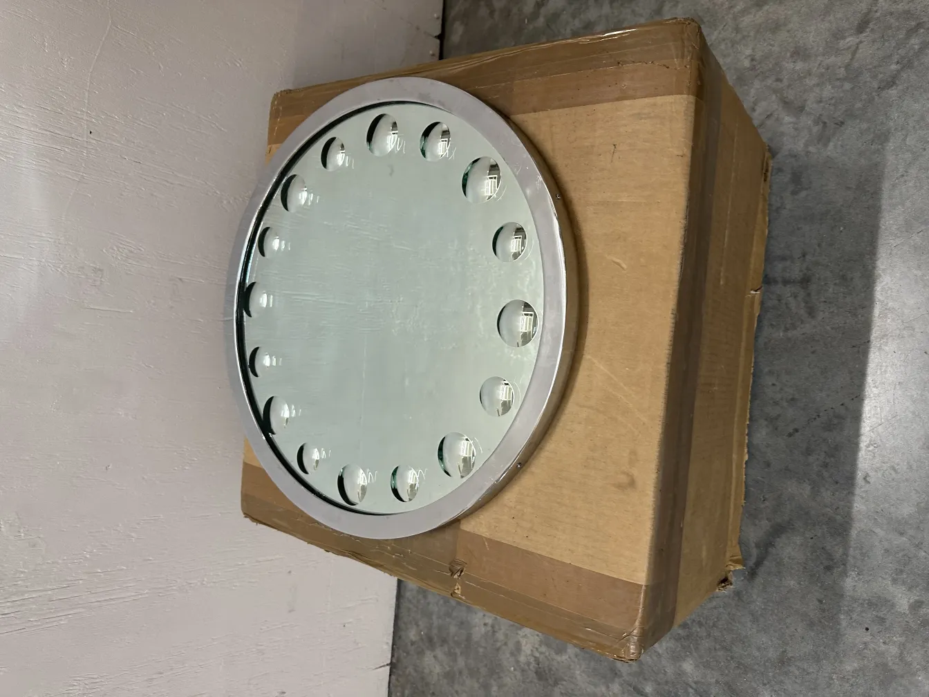 antique round mirror with visible details, cardboard background