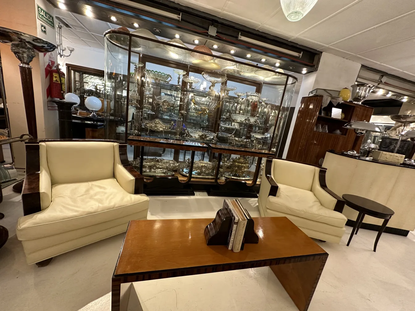 Fermalibri antichi decorativi su un tavolo moderno, con poltrone e una vetrina di antiquariato.