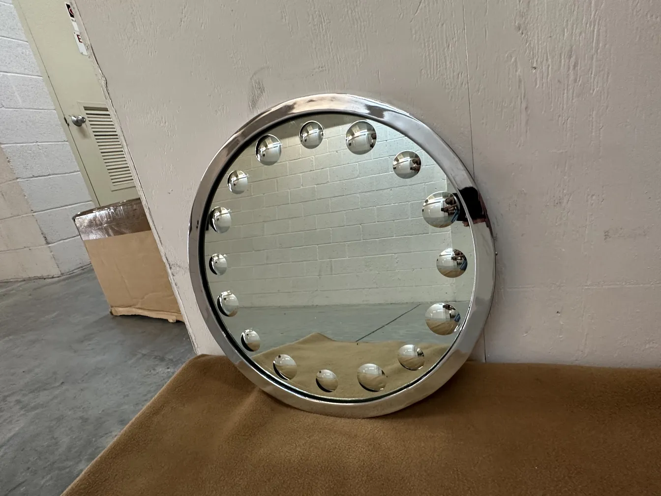 Round antique mirror with circular decoration and lights. Neutral background.